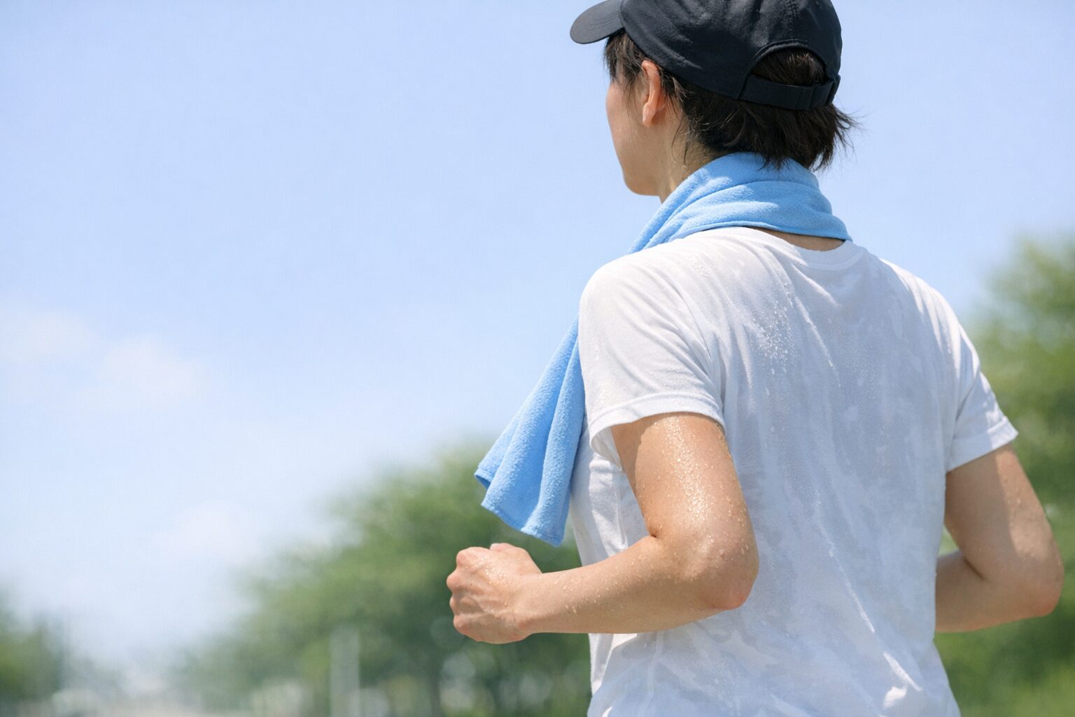 炎天下で冷感タオルを首に巻いてウォーキングする人（冷感タオル 持続時間のイメージ）